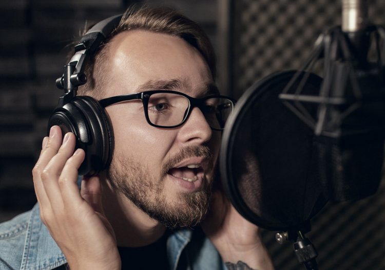 Man doing a voiceover in front of a microphone with headphones on.