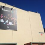 A large banner of the ABC TV show "Black-ish" is displayed on the exterior of a building marked as "Stage 4." The poster features the cast, suggesting a promotional or filming location related to the show.