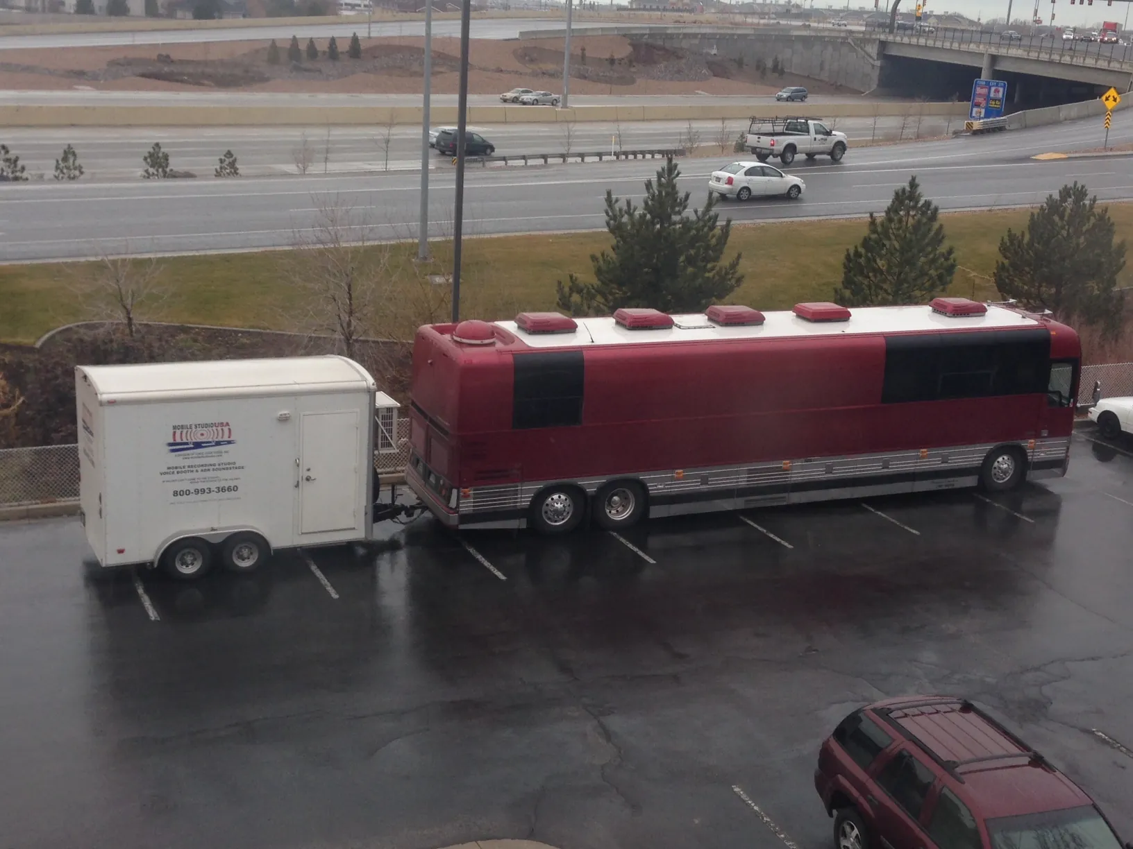 The "Mobile Studio USA" trailer is seen attached to a large maroon tour bus belonging to the band Pentatonix, parked in a lot. The trailer setup indicates it’s ready to support audio recording needs on the road.